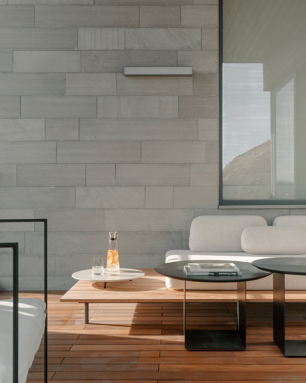 Terrace-side living area with a stone wall, a low table and armchairs
