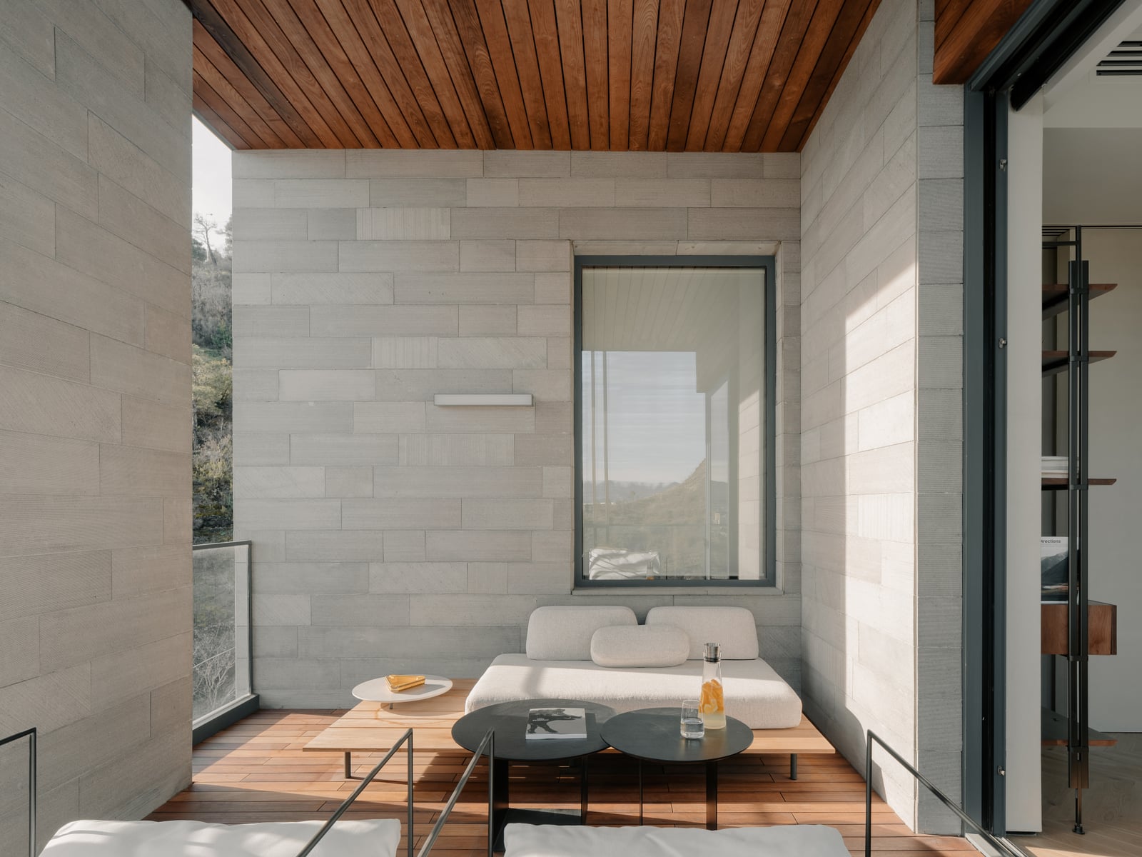 Terrace lounge with a timber ceiling, a sofa and a glazed wall