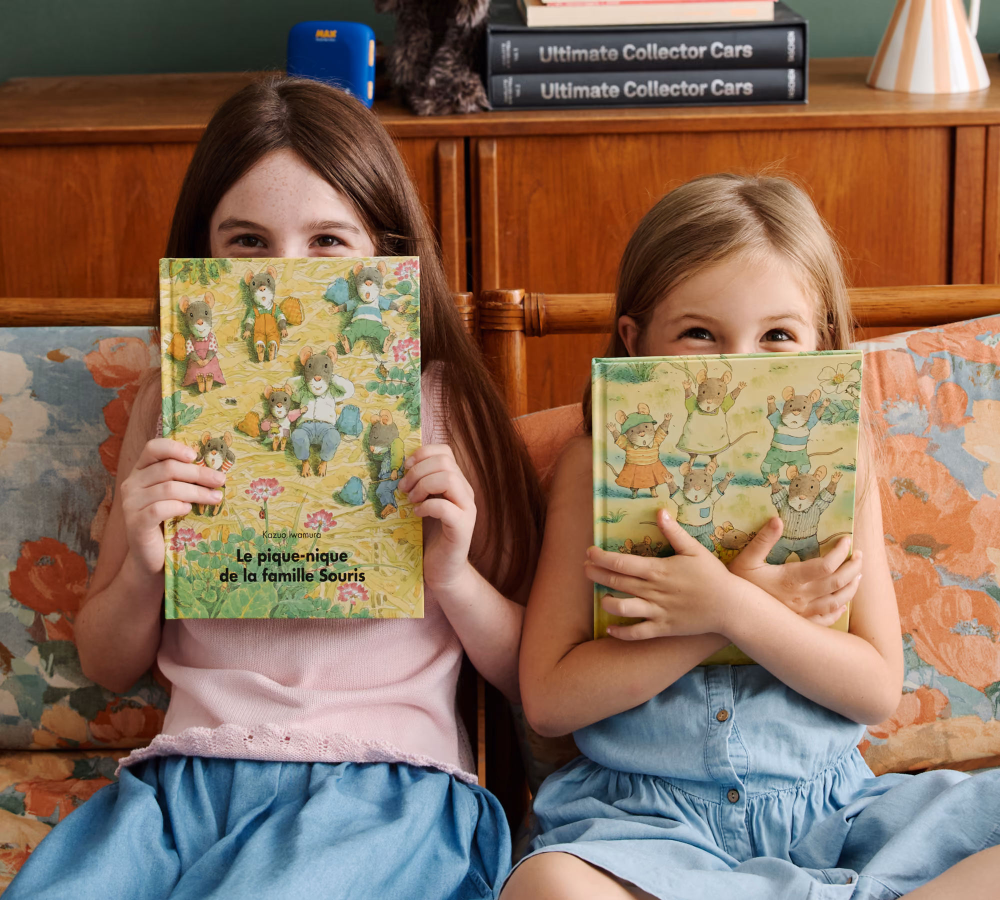 Deux filles assises sur un canapé avec chacune un livre illustré de la famille Souris de l'École des Loisirs.