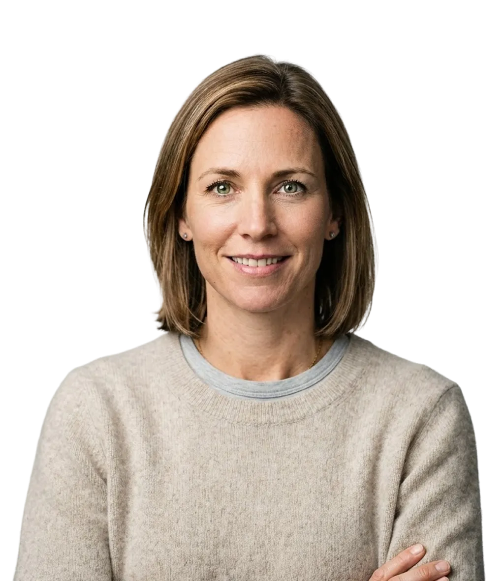 Smiling woman with shoulder-length light brown hair wearing a beige sweater and light gray shirt, arms crossed.