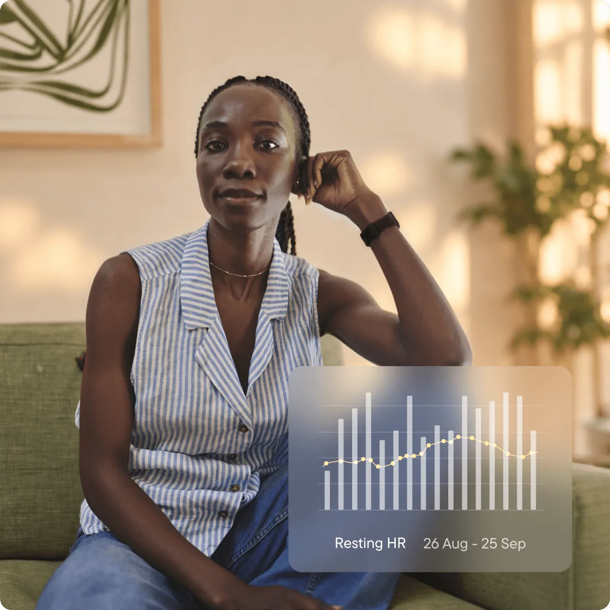 A woman sitting on a sofa at home, wearing a Visible band on her wrist. An overlay shows a bar chart of her resting heart rate from 26 August to 25 September.