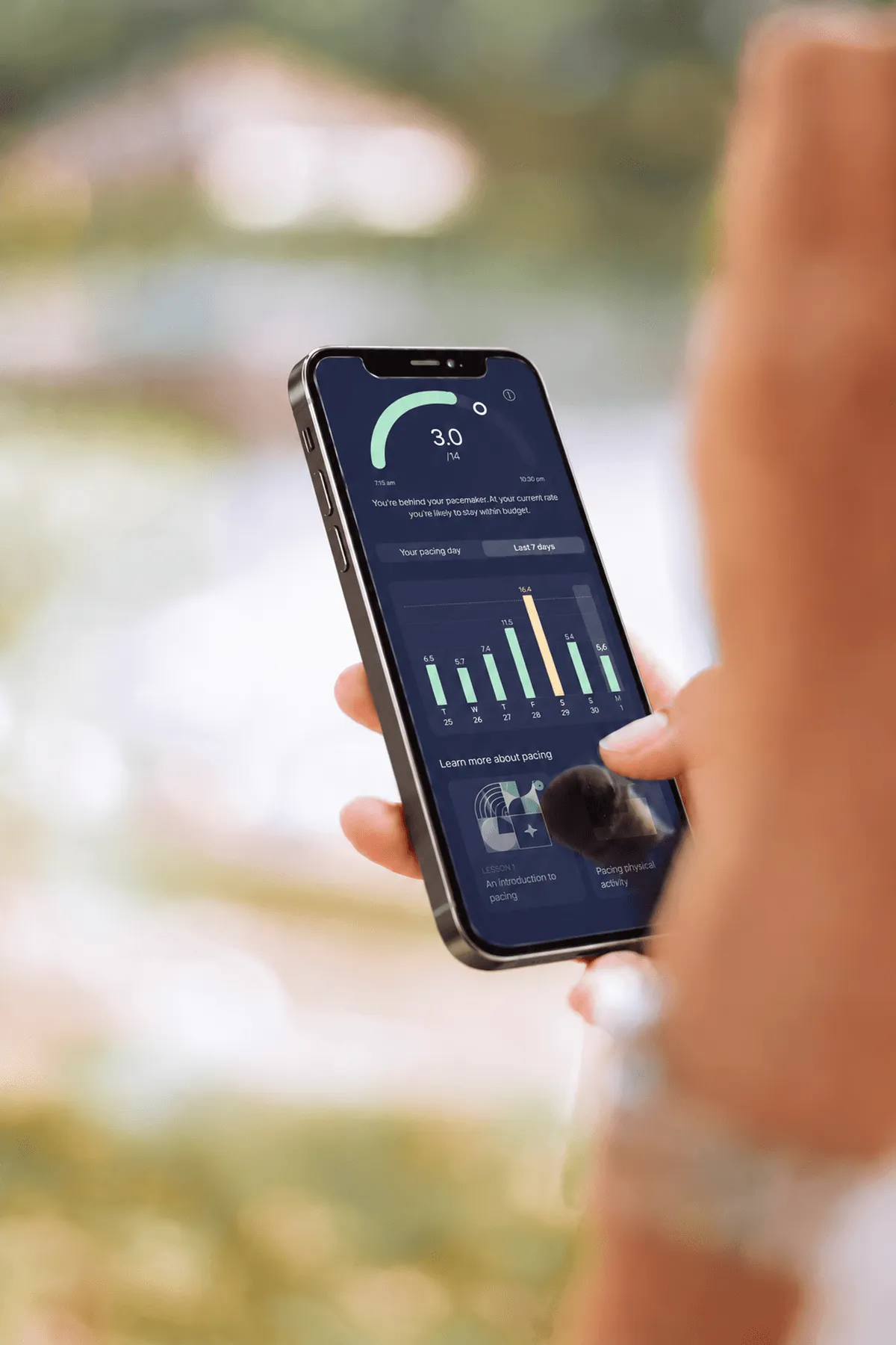 Close-up of a hand holding a phone with the Visible app open, showing 3.0 out of 14 PacePoints used so far today. There's also a bar chart of the last seven days, with one day showing energy use well above the rest.