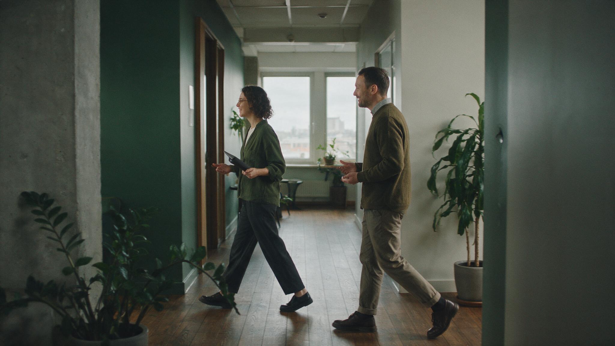 Two colleagues walking through a quiet office corridor
