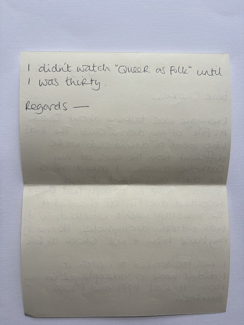 Handwritten note on cream paper saying "I didn't watch 'Queer as Folk' until I was thirty. Regards -" with faint reverse text visible below.