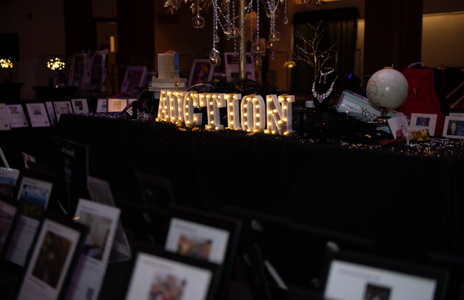 Silent auction tables lit by marquee letters spelling AUCTION