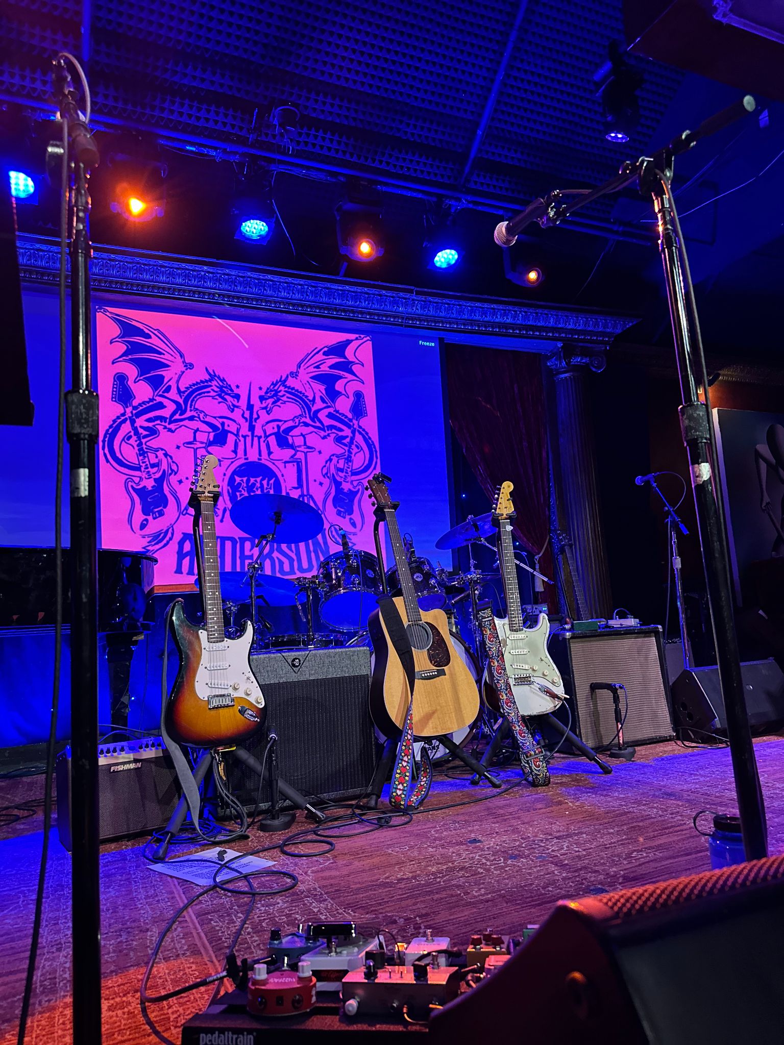 Instruments set up on stage before the Music Benefit, with the Anderson logo projected behind