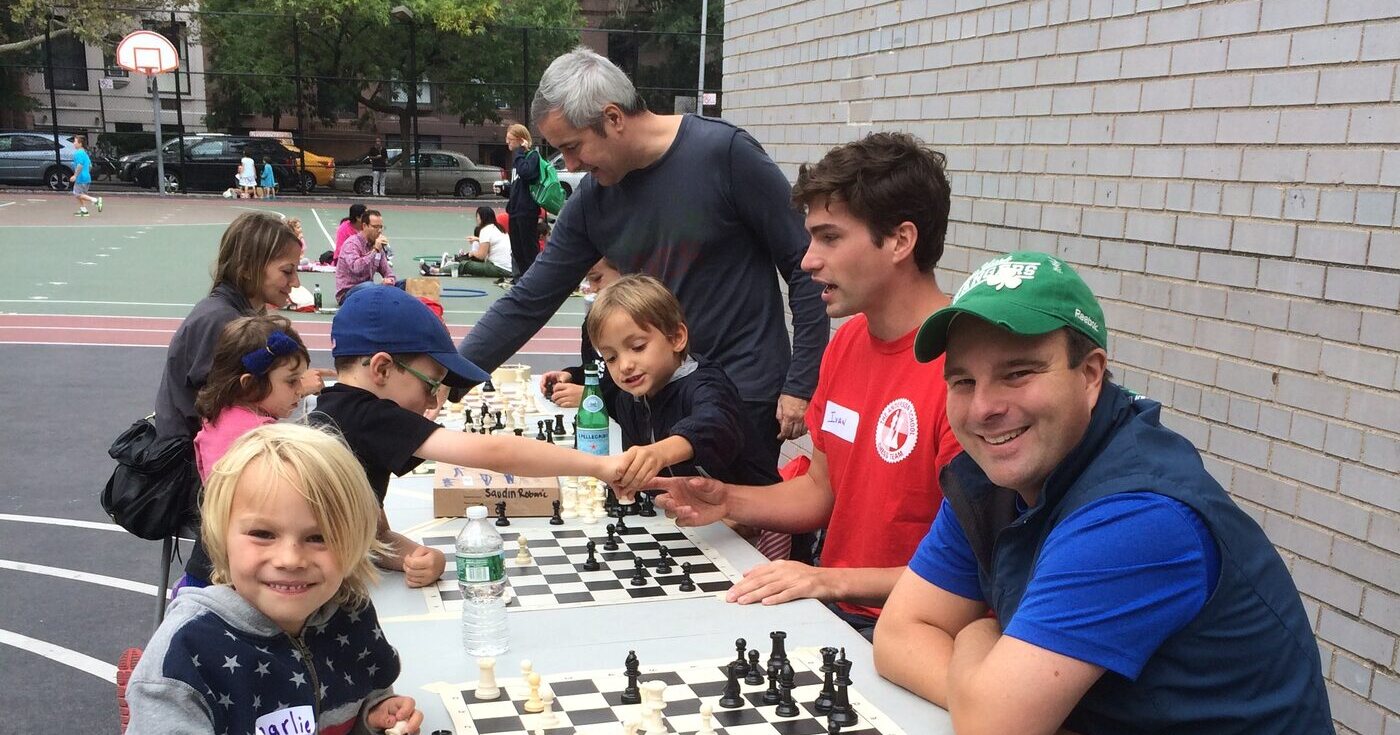 Anderson parents and children playing chess together at tables in the schoolyard