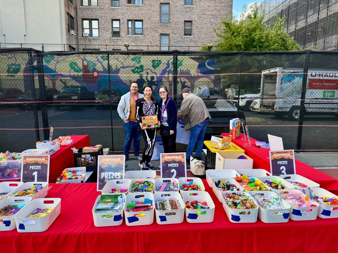 Volunteers behind tables of prizes at Spooktacular