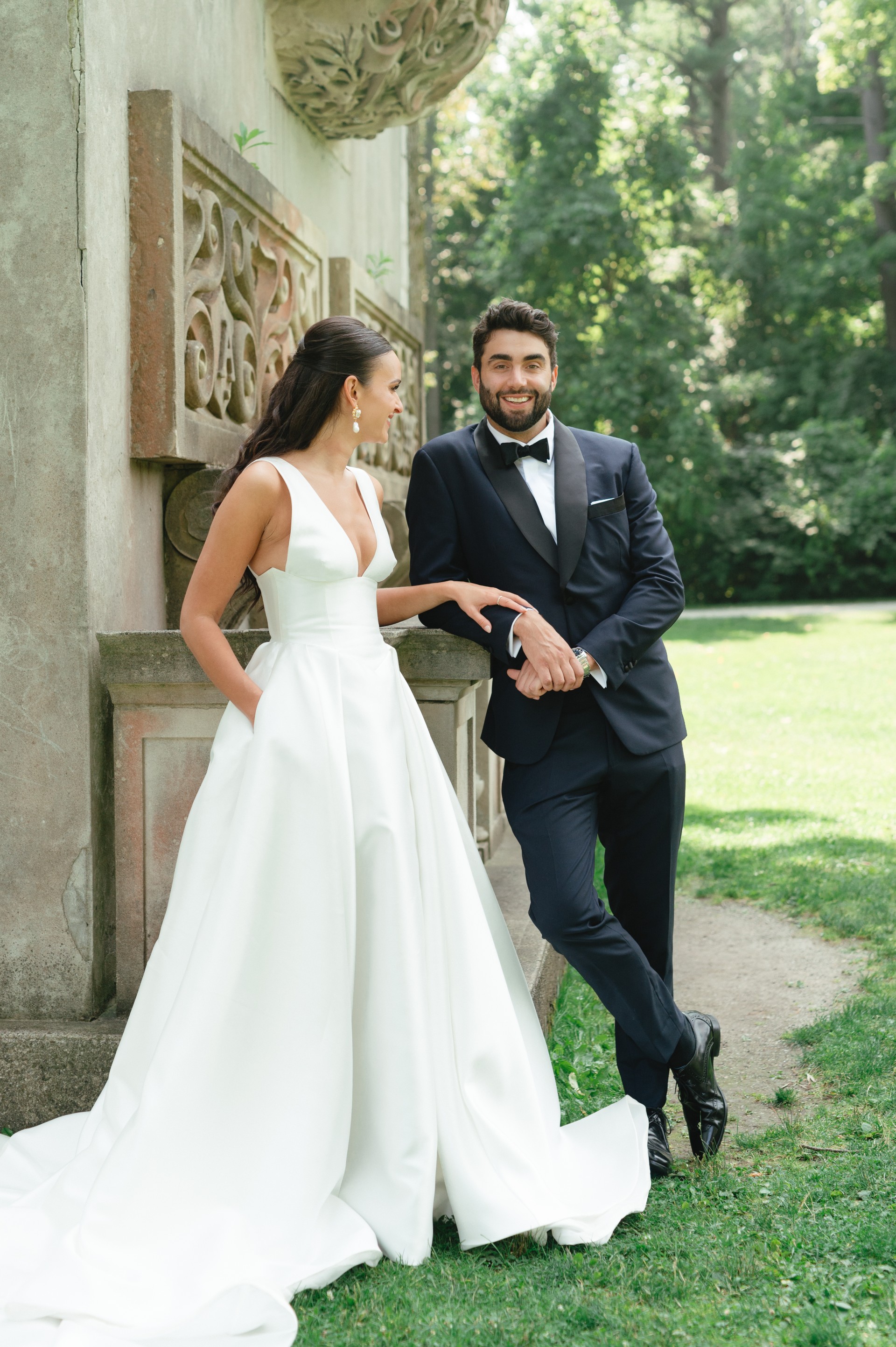 Bride and groom outdoors, groom wearing a navy tuxedo with black bow tie