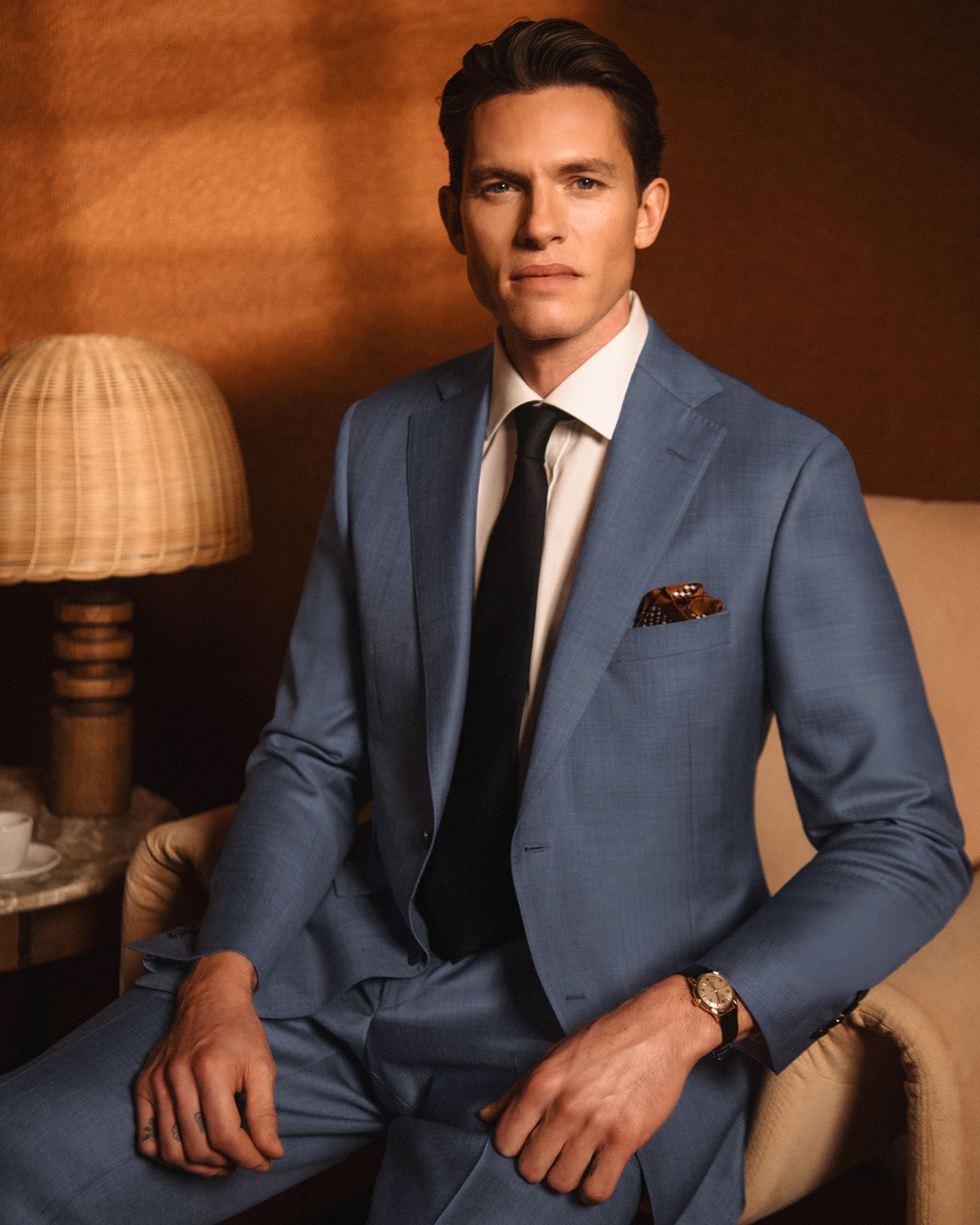 Man wearing a tailored blue suit with white shirt and black tie