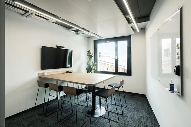 Raum mit einem Monitor und Kamera vor einem Tisch mit 4 Stühlen