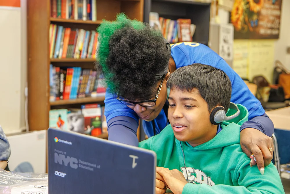 Teacher helping a student work on an NYC school Chromebook