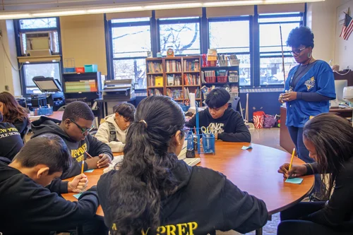 Teacher guides students working together at a round classroom table