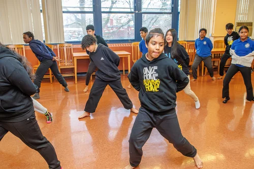 Students practicing dance moves together in a school classroom