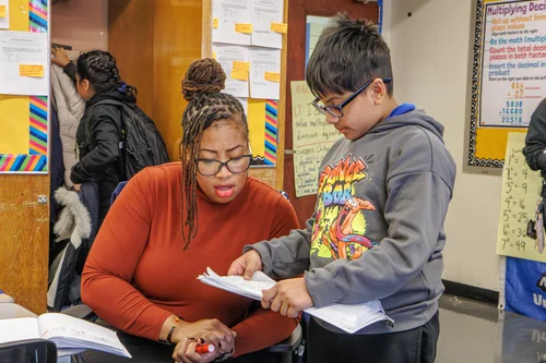 Teacher helping a student review paper in a classroom