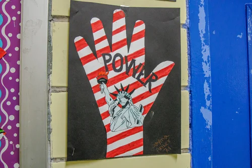 Student artwork showing raised hand with Statue of Liberty and word Power
