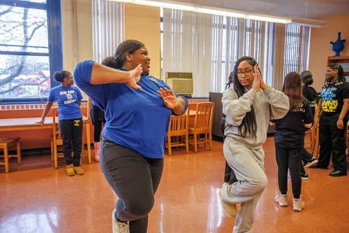 Students practicing dance moves together in a school classroom
