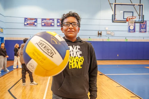 Student holding a volleyball in school gymnasium