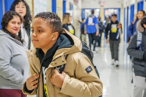Student with backpack walking through a busy school hallway
