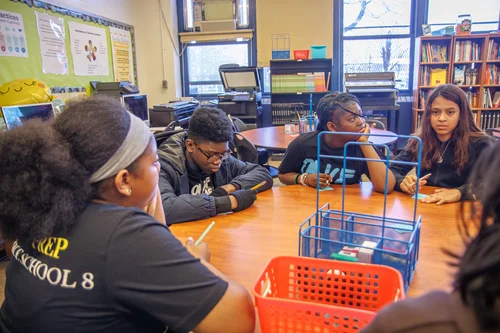 Students in PREP School 8 shirts collaborating at a classroom table