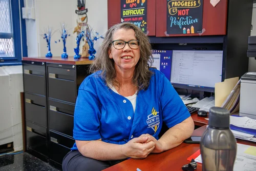 Staff member smiling at desk wearing New Prep school shirt