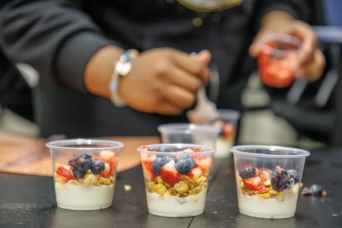 Student preparing yogurt parfait cups with granola and fresh berries