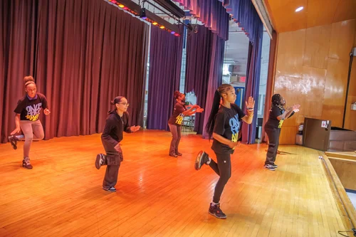 Students performing a hip hop dance routine in school auditorium