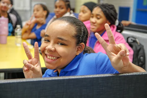 Smiling student making peace signs in a classroom
