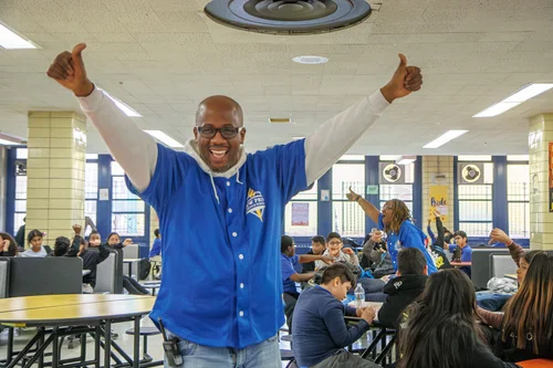 Teacher giving thumbs up with excited students in school cafeteria