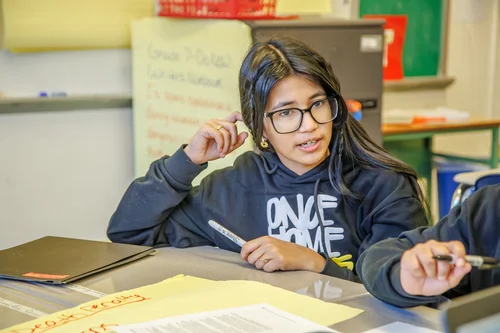 Student speaking and gesturing during a classroom discussion