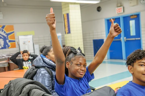 Student giving two thumbs up in school cafeteria