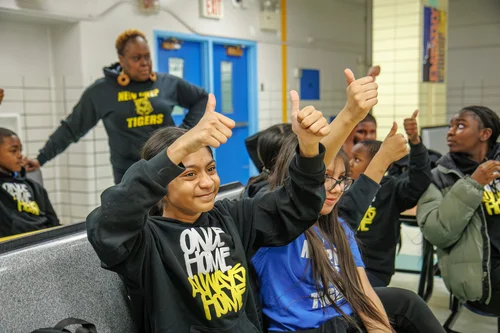 Students giving thumbs up in school hallway wearing Tigers sweatshirts
