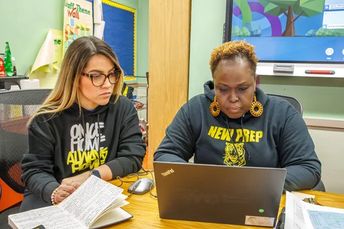 Two New Prep staff members collaborating at a laptop in a classroom