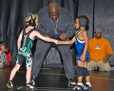 Coach shaking hands with two youth wrestlers before a match