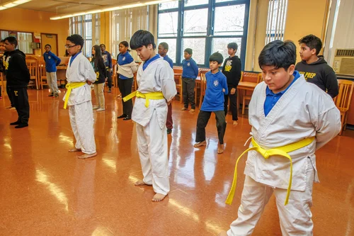 Students in white gi and yellow belts practicing martial arts indoors