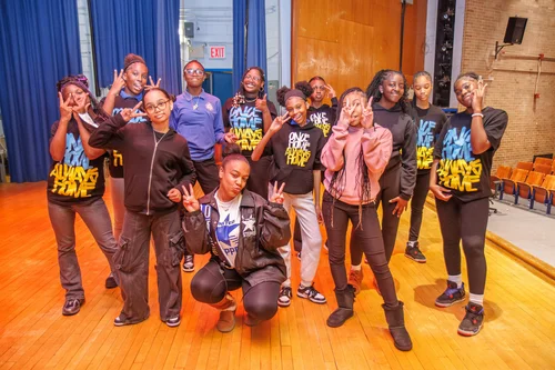 Students posing together in matching black shirts in school auditorium