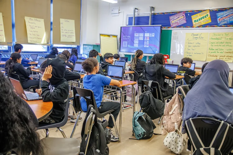 Students working on laptops in a middle school classroom