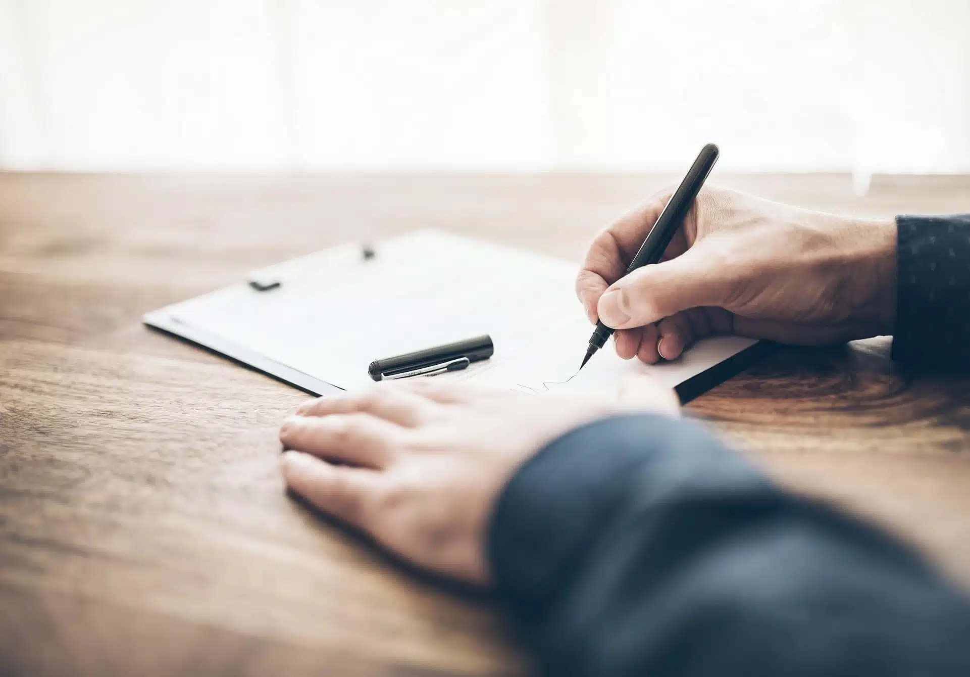 man signing a document - How to Dissolve an LLC in Maine