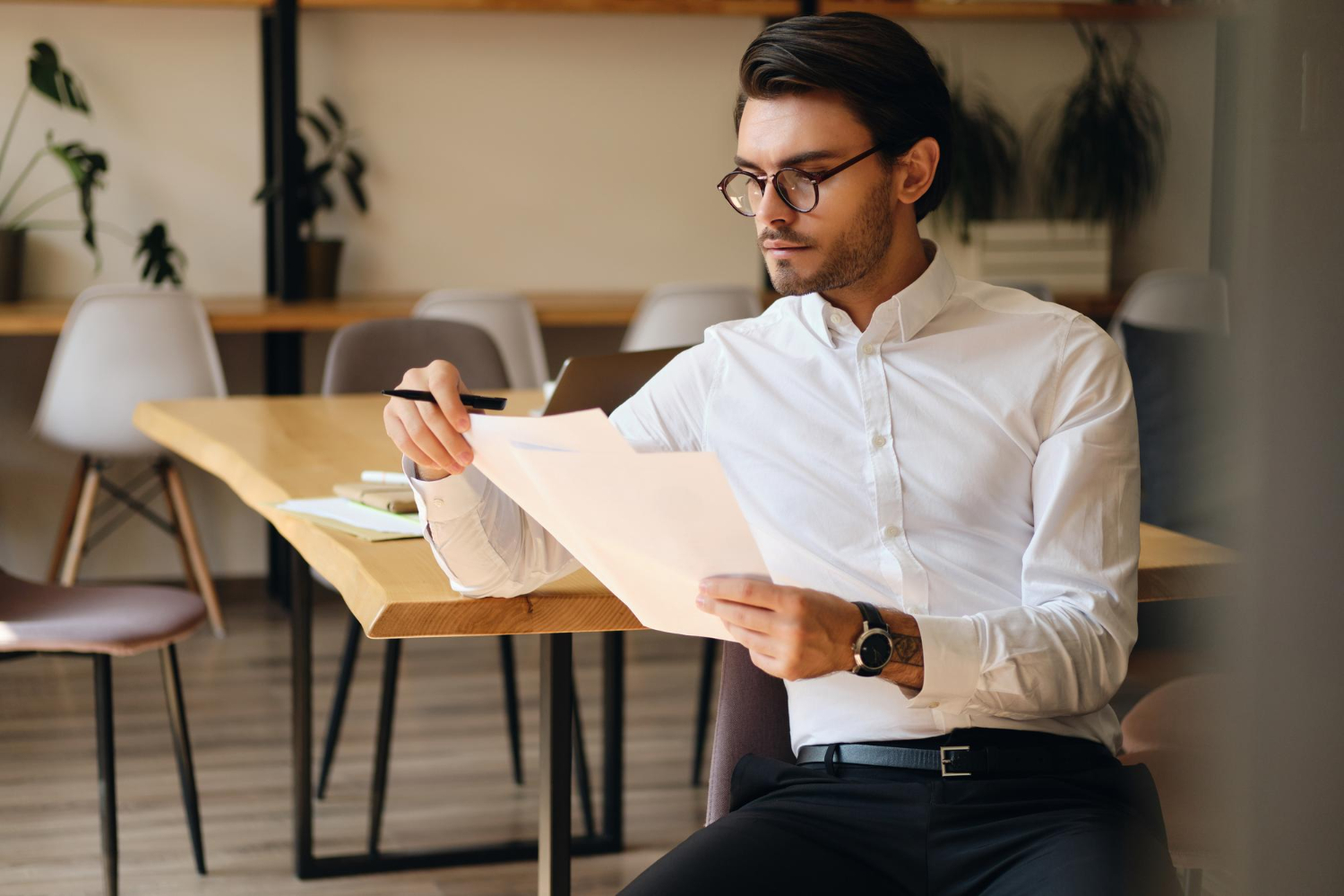 person wearing glasses reading a document - How To Dissolve an LLC in New Mexico