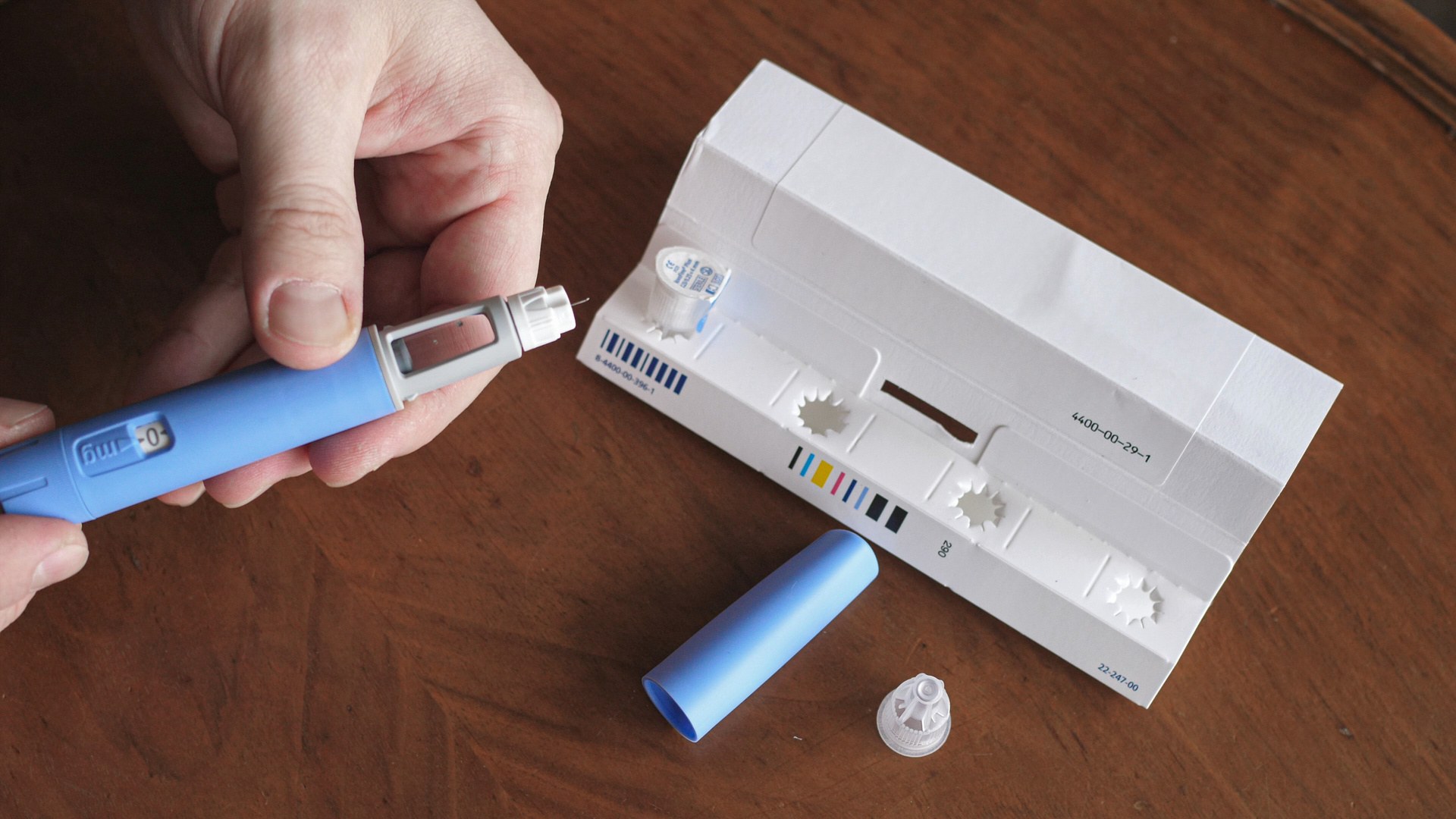 Blue injector pen and packaging on a wooden table
