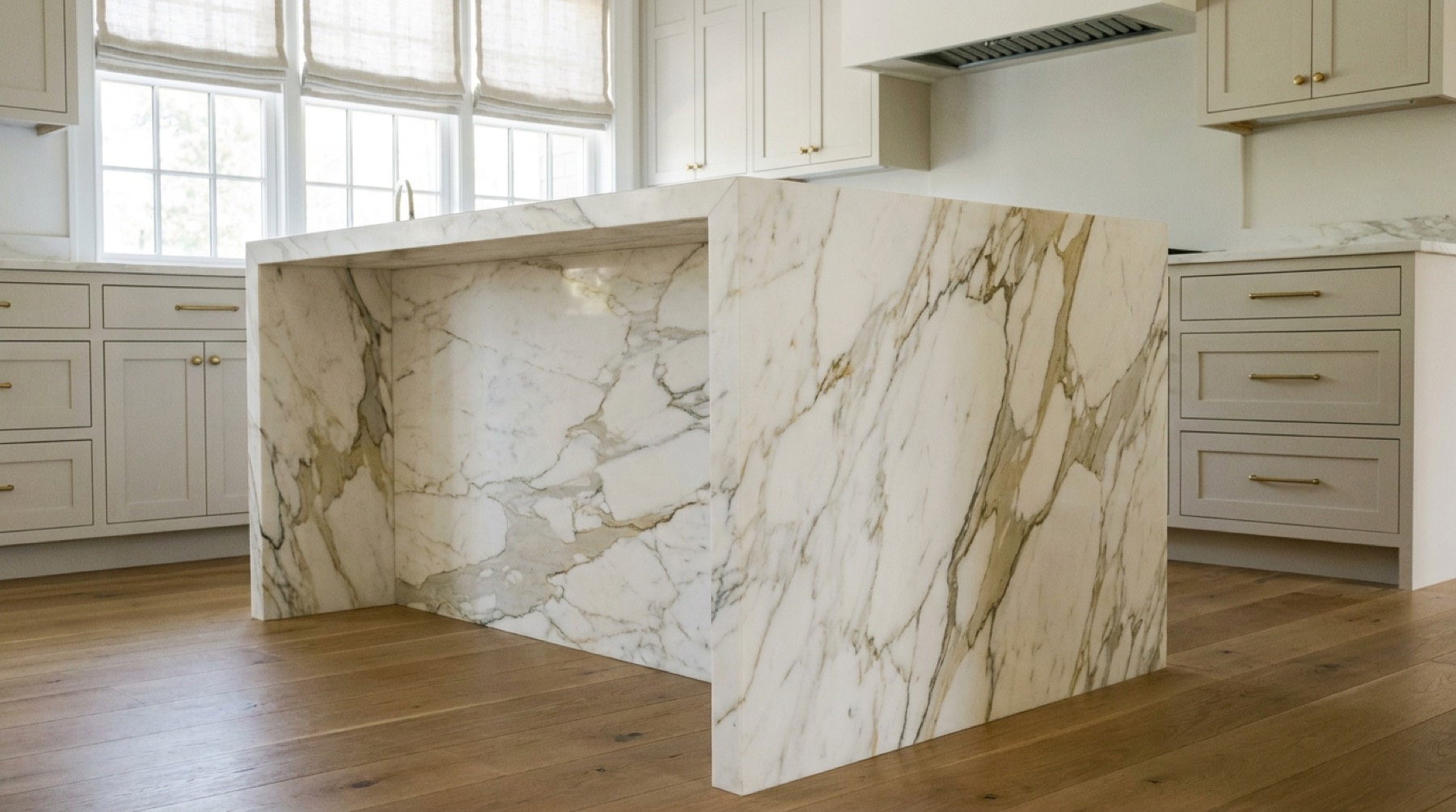 Kitchen island in Calacatta marble with a mitred waterfall edge, veining continuing around the corner