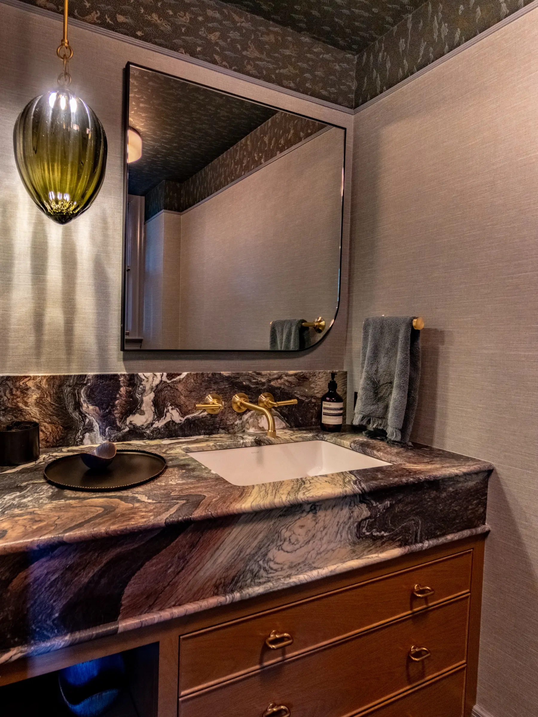 Fusion quartzite powder room vanity with a mitred apron front, undermount sink and wall-mounted brass faucet, fabricated by CMG
