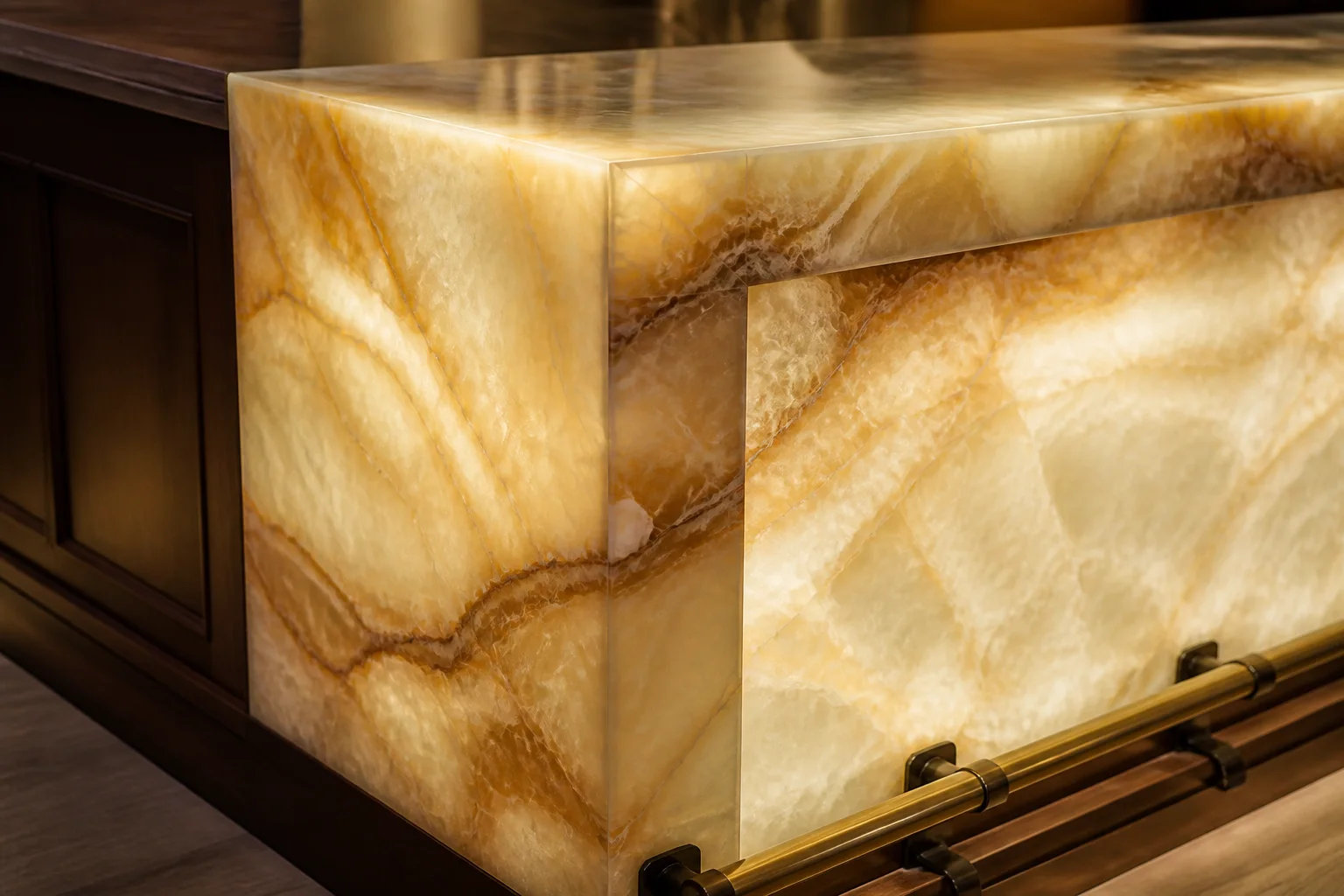 Mitred corner of a backlit honey onyx bar front with a brass foot rail