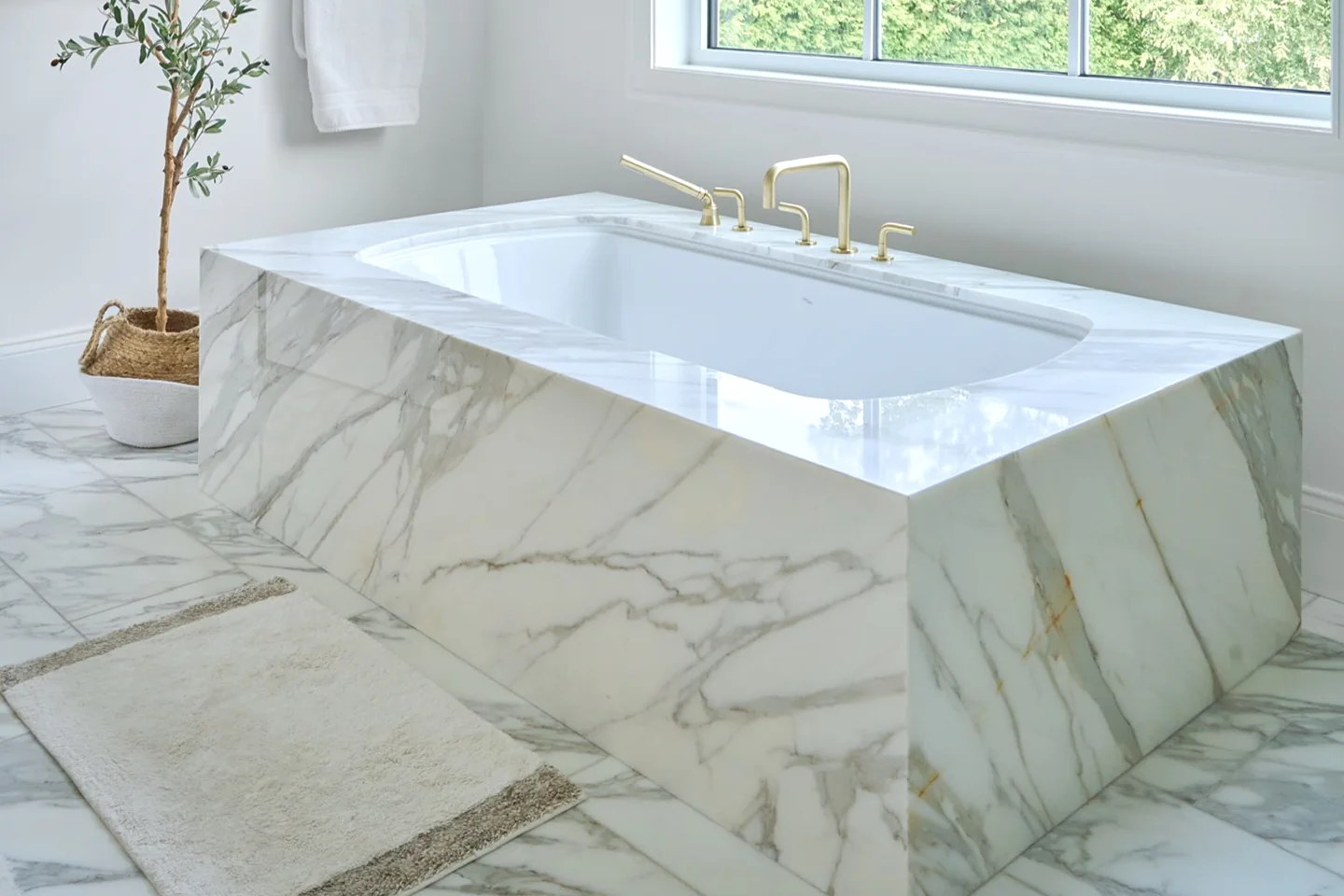 Calacatta Borghini marble tub deck and mitred apron with brass fixtures.