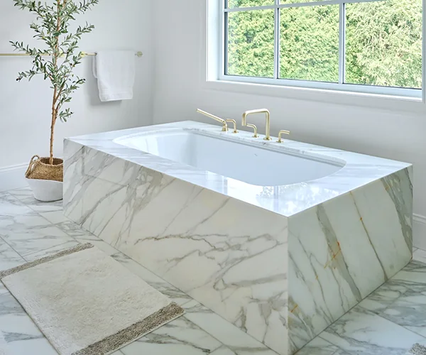 Calacatta Borghini marble tub surround with a mitred apron and brass fixtures.