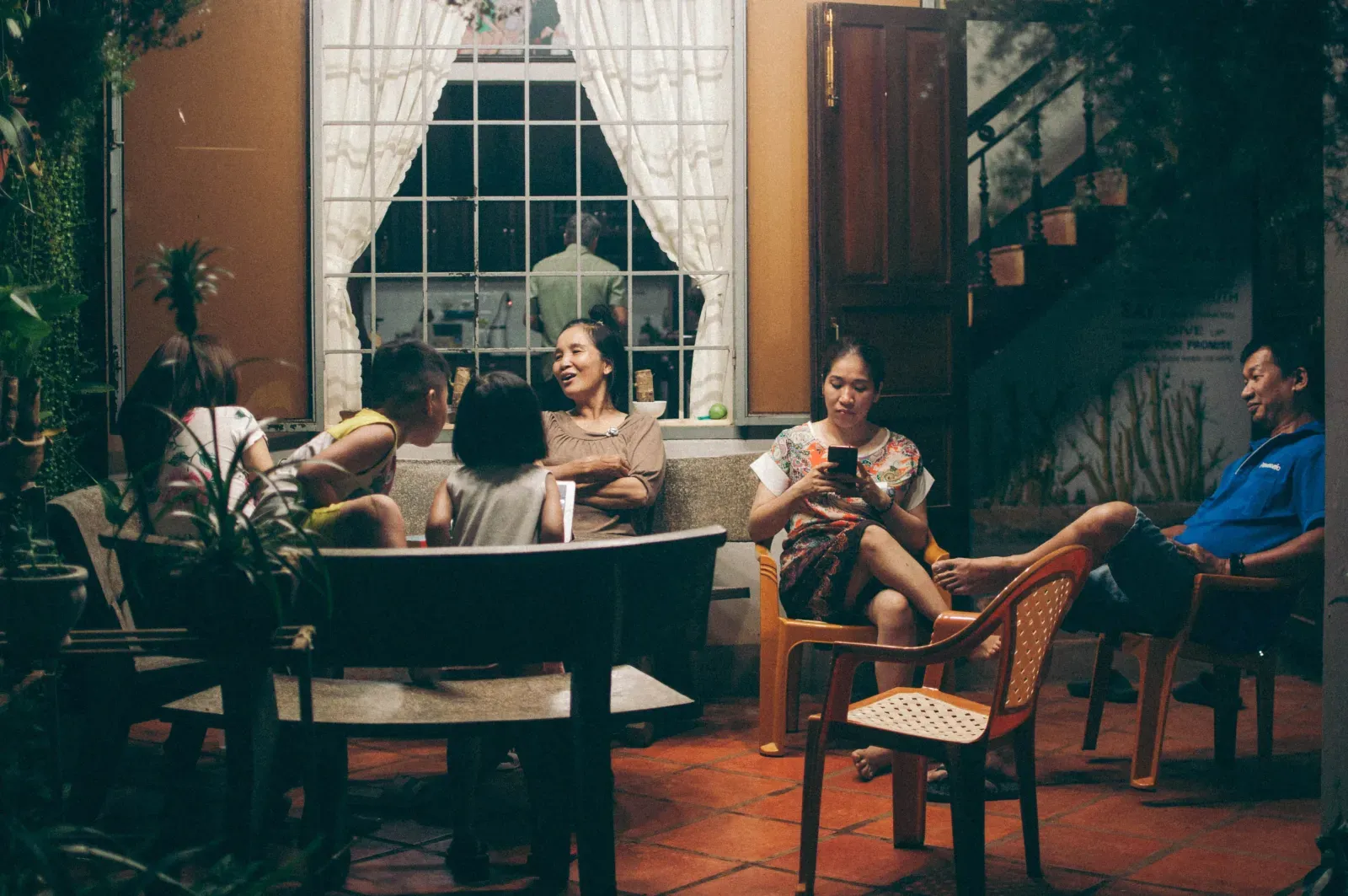 Several people gathered on a porch in warm evening light.