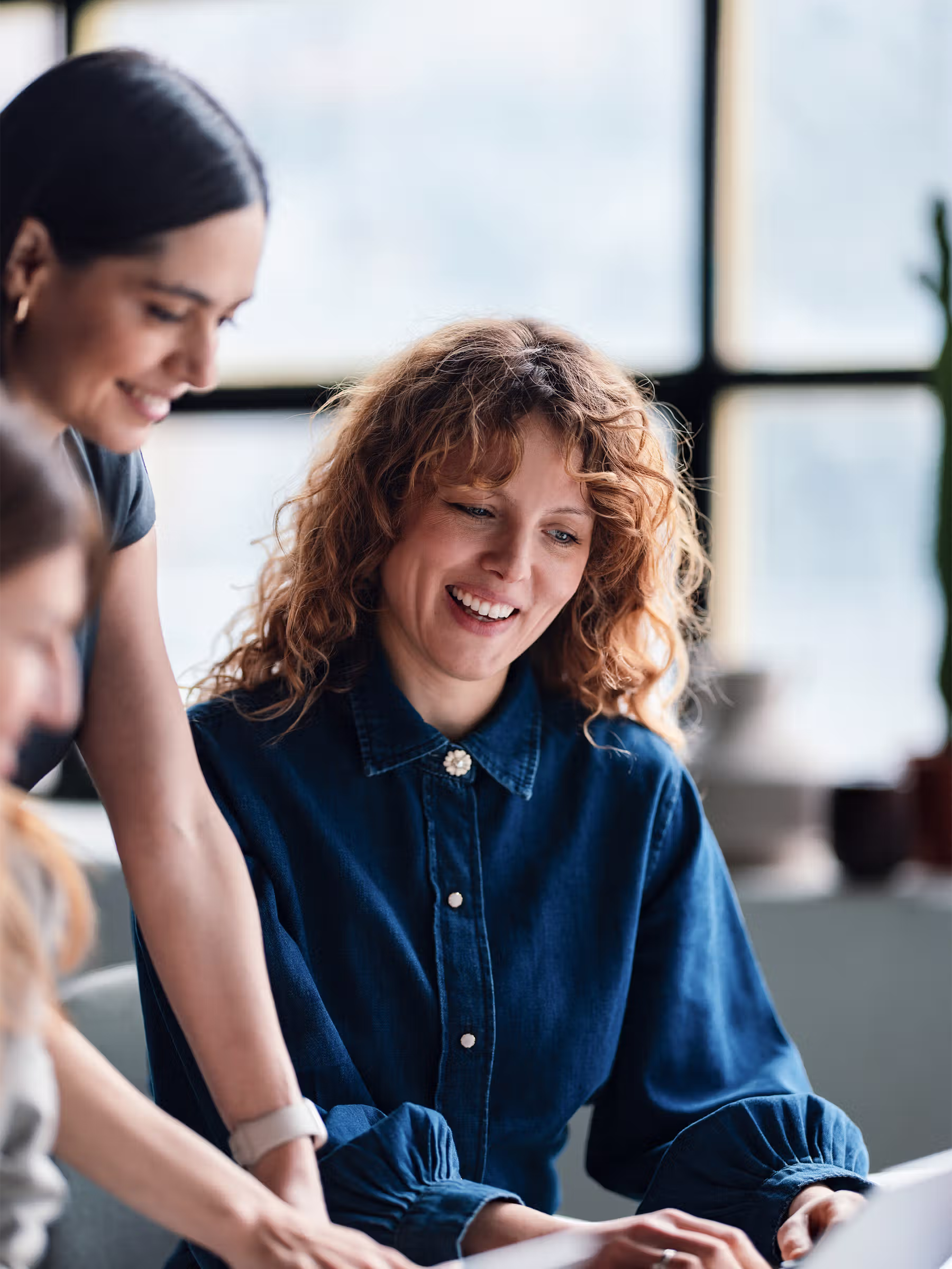Cross-functional team discussing work together at a shared desk in a contemporary office.