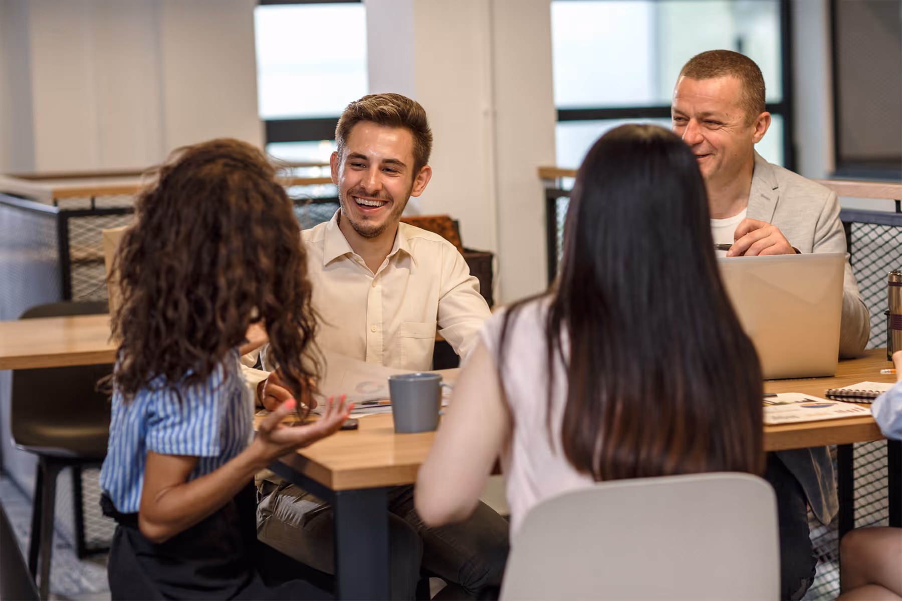 Four colleagues having a lively discussion around a table in a modern office.