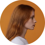 Profile of a young woman with long red hair against an orange background.