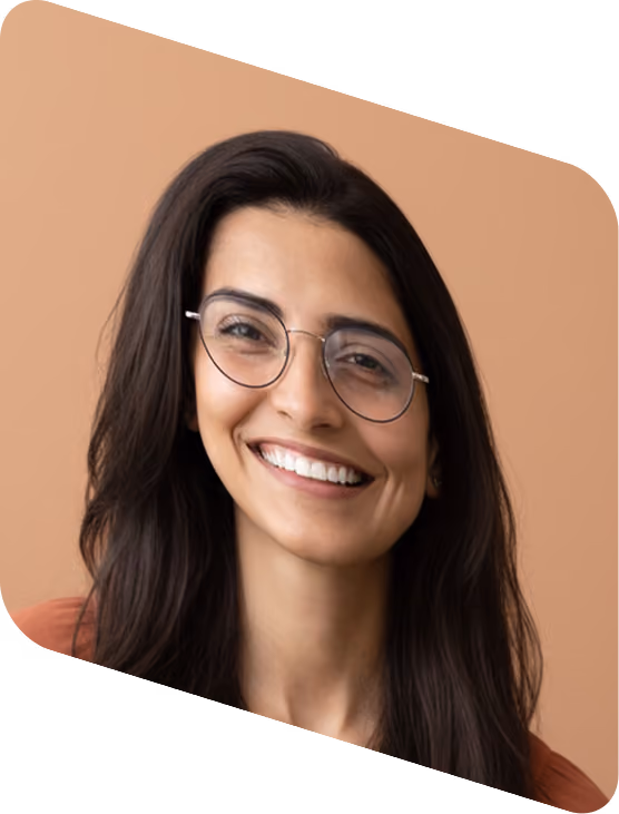 Smiling woman with long dark hair and round glasses against a light brown background.